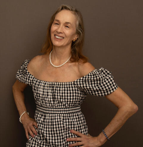 headshot of Joan in a black and white checkered dress.